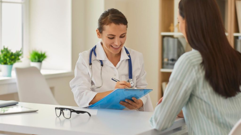 doctor writing information while talking to patient