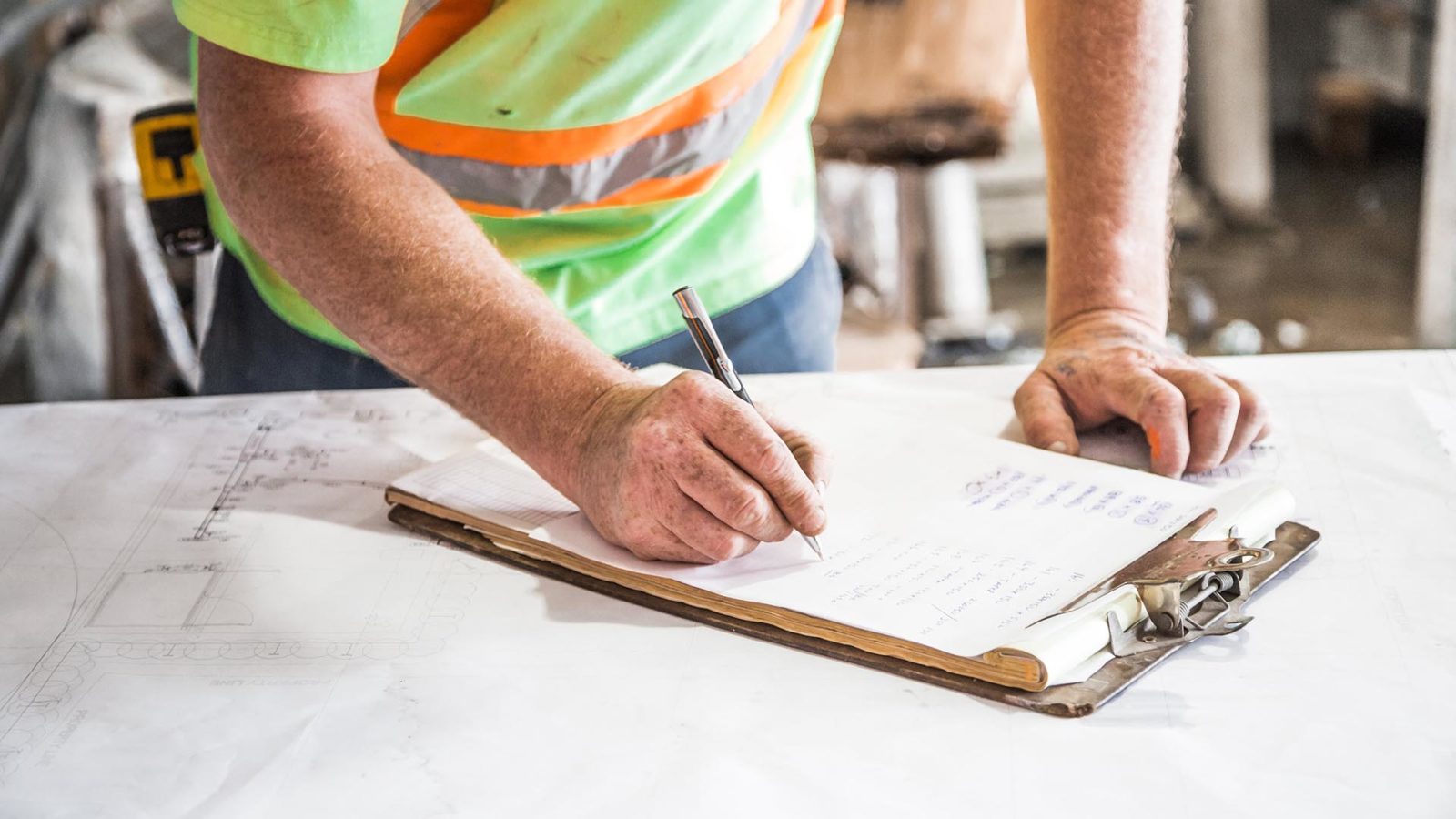 worker at jobsite filing out paperwork on clipboard