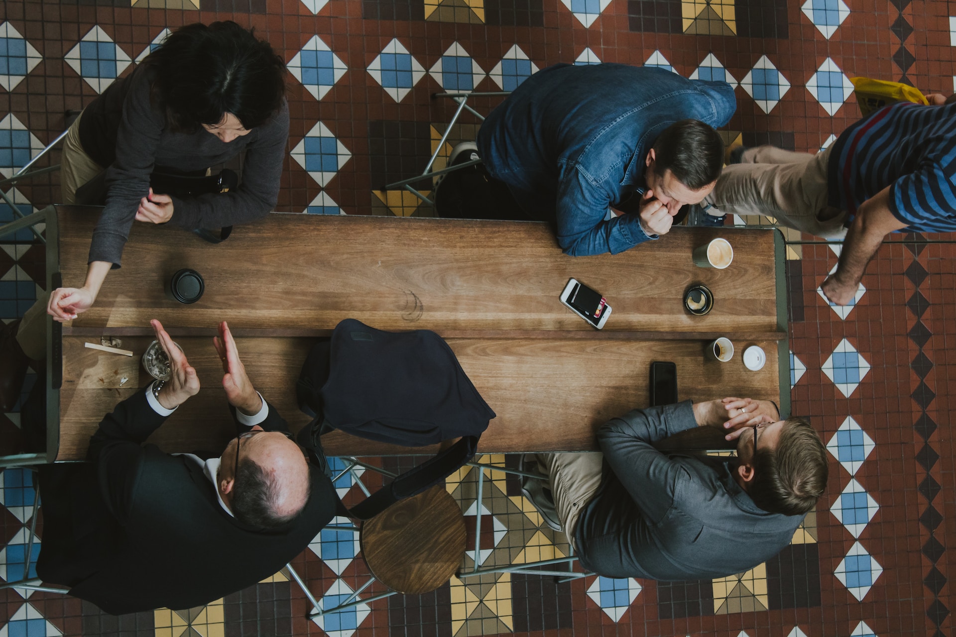Arial view of a group of people sitting and chatting at a table with coffees